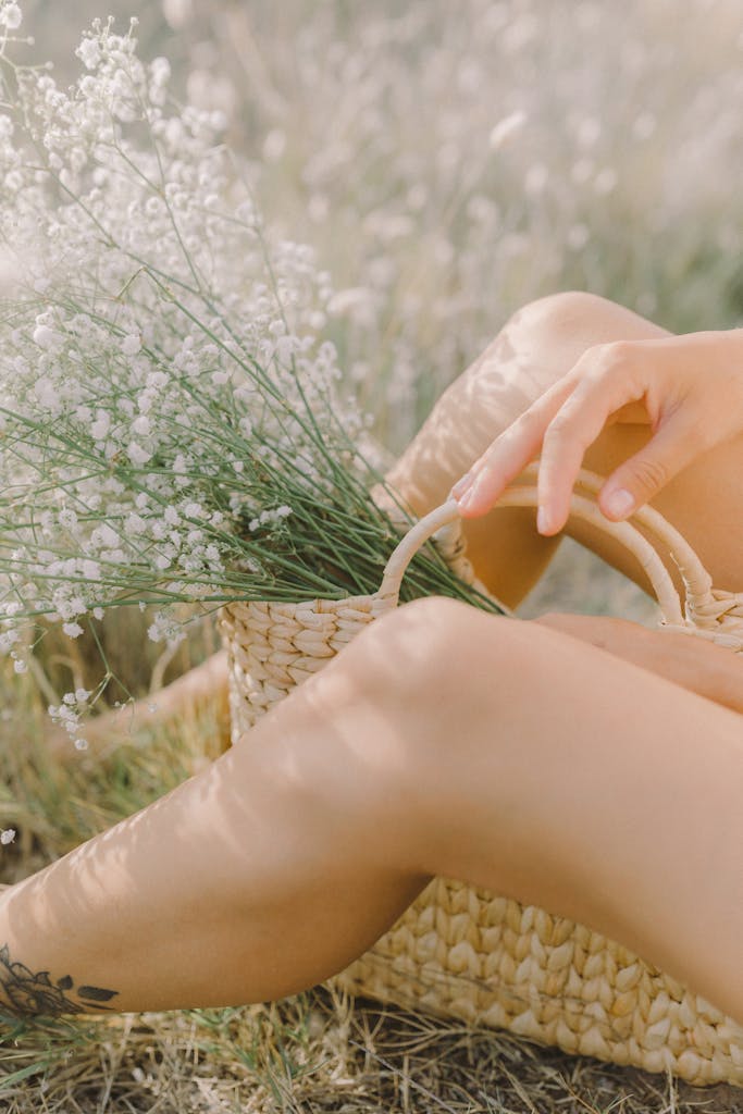 A serene scene of a person resting outdoors with a straw basket filled with flowers.
